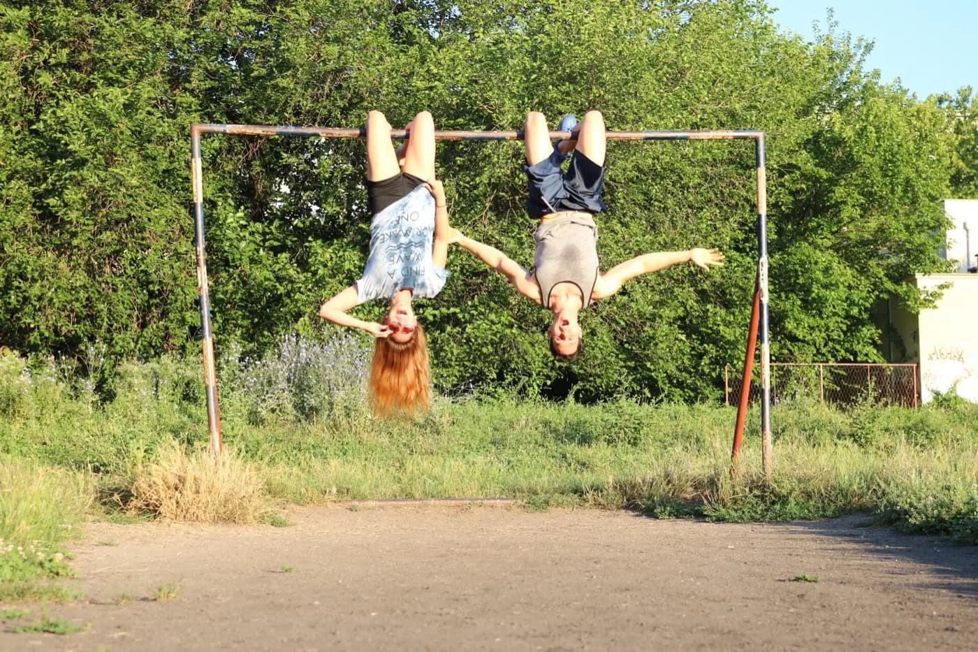 Adam and Amie Watanabe hanging upside down from a bar, laughing
